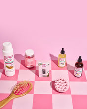 Load image into Gallery viewer, A collection of hair care products Hair Plus displayed on a pink checkered background, including bottles of growth serum, a brush, and a scrub and gummy pack.